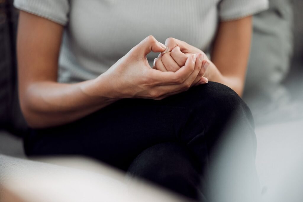 Person sitting with their hands clasped during a conversation about mental wellbeing