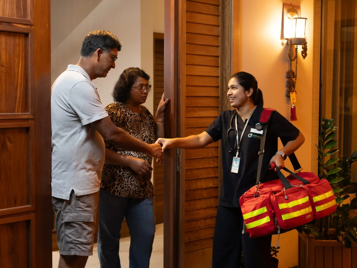 An OCS Médecins doctor with her medical bag being welcomed into a Mauritian home at night