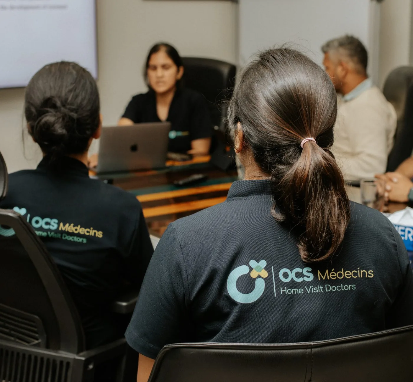 The OCS Médecins team in a boardroom briefing, the OCS logo on their shirts.