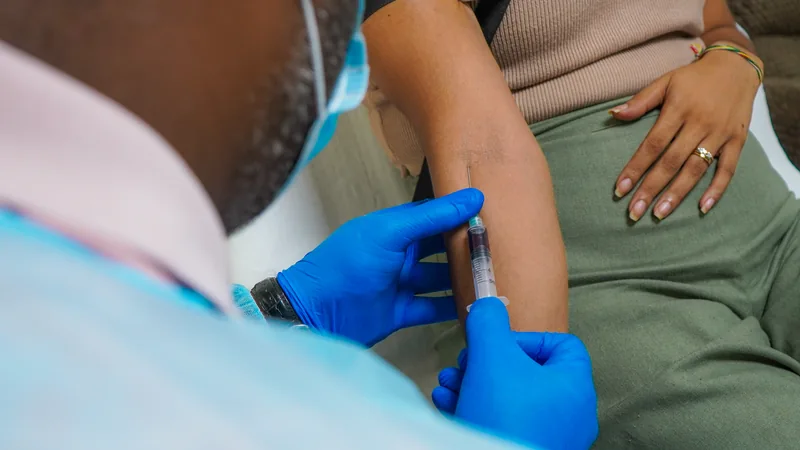 Gloved clinician collecting a blood sample from a patient’s arm.