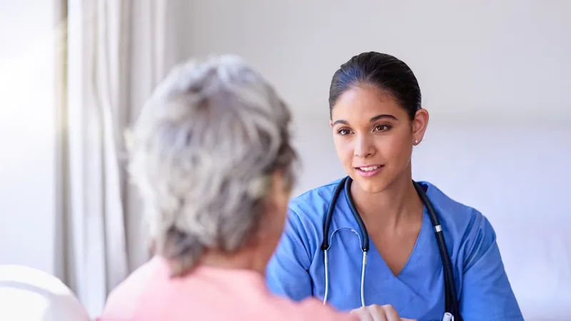 Healthcare professional speaking with an older woman.