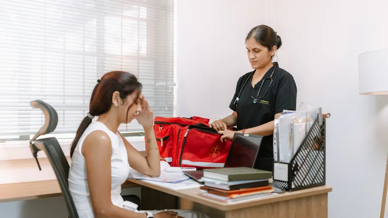 Woman holding her temple while an OCS clinician prepares for a consultation.