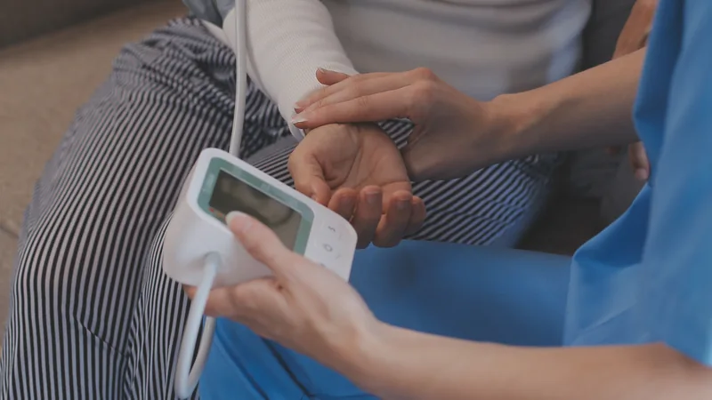 Close view of a clinician checking a patient’s wrist blood pressure.